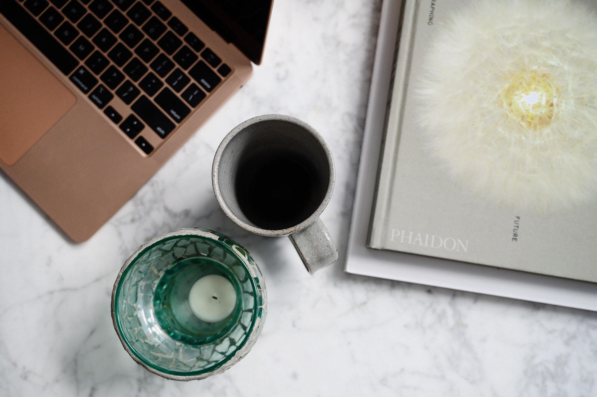 Picture of a coffee mug, book, and laptop on a table